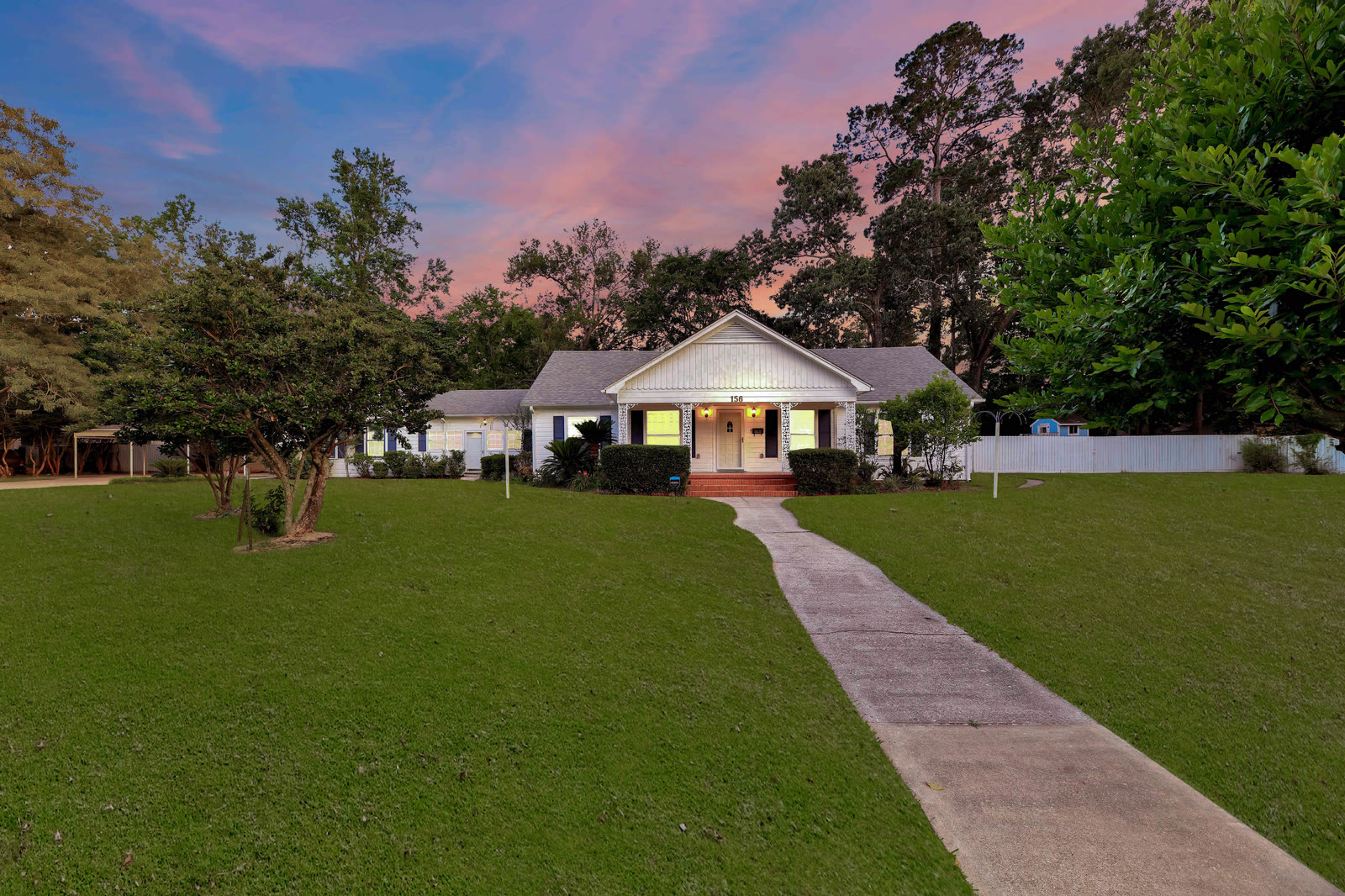 White home with a wide lawn at twilight